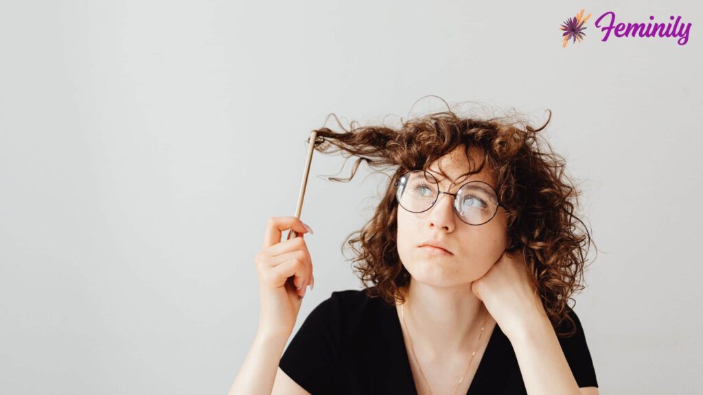 Woman thinking while twisting her hair with a pencil